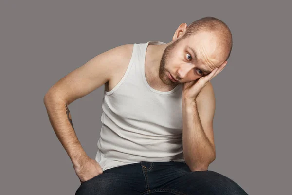 Bald guy in a white t-shirt sits on a chair and thinks about problems with money, loneliness, payments, work and divorce — Stock Photo, Image