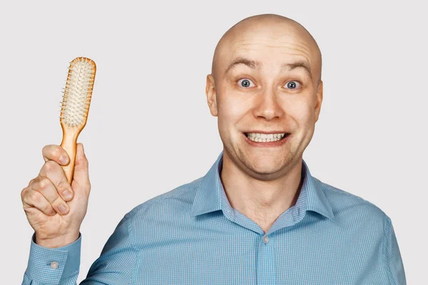 Un hombre calvo con alopecia sostiene un peine en su mano. concepto absurdo —  Fotos de Stock
