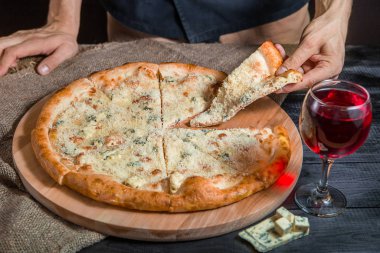 İtalyan pizzası. Tahtada 4 peynirli. Pizzacı ve şaraplı.
