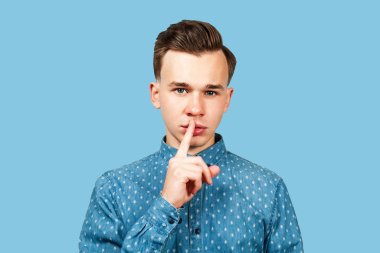 Mavi gömlekli, parmakları ağızdan ağıza genç bir adam. Beyaz adam sessiz hareket ediyor, izole edilmiş..