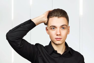 Pompadour saçlı, siyah gömlekli, ciddi yüzlü genç bir adam.