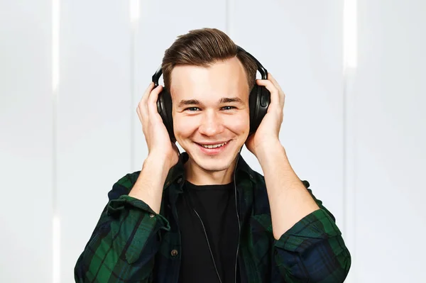 Ένας λευκός νεαρός ακούει μουσική στα ακουστικά. πορτρέτο ενός καυκάσιου όμορφου άντρα — Φωτογραφία Αρχείου