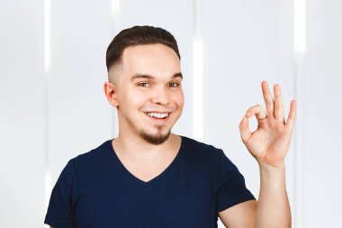 Adam gülümsüyor ve işaret veriyor. Tamam, kapüşonlu giyinmiş.