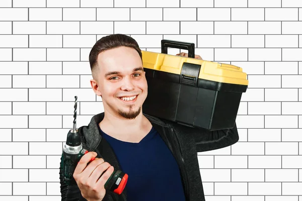 Jonge man met gereedschapskist en schroevendraaier, Portret van een knappe reparateur met boor in het heldere interieur — Stockfoto