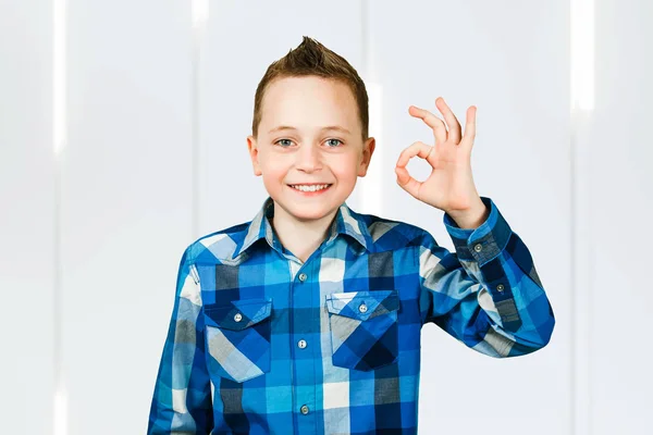 Porträtt av ung pojke skratta och visa OK tecken på en vit bakgrund — Stockfoto