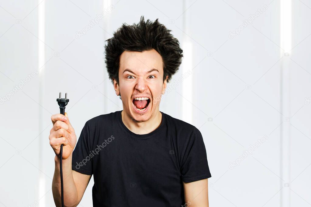 long hair guy holds an electric plug with a cable in his hand on a white background.