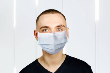 Koruyucu maske takan mutsuz, üzgün genç adam virüs enfeksiyonunu ve kirliliği önler..