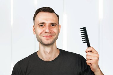 Gülümseyen genç adam saç tarağını tut. Berber dükkanı için.