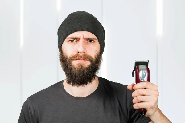 Junger Bärtiger Mann Mit Hut Hält Trimmer Und Schneidet Sich — Stockfoto