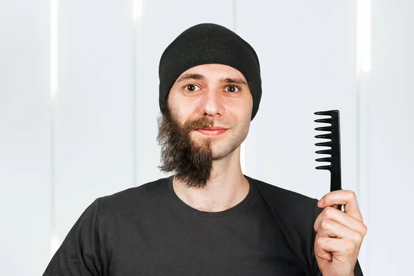 Man with half shaved beard surprised with smile hold hair comb