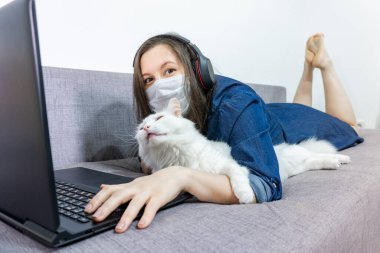 Kız öğrenci, video öğretmeniyle internetten kulaklık dersi alıyor, mutlu genç kadın evde ders çalışıp, ders izliyor. Covid-19 Coronavirüs.