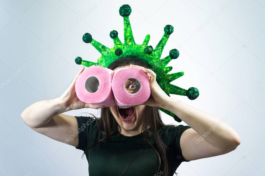 Woman holds two rolls of toilet paper in her hands and looks at them like with binoculars. Virus, epidemic, quarantine.