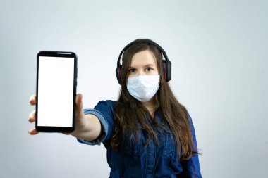 Tıbbi maskeli kadın, Corona virüsündeki kendini izolasyon ve karantina süresince evden cep telefonunun boş ekranında görünüyor..