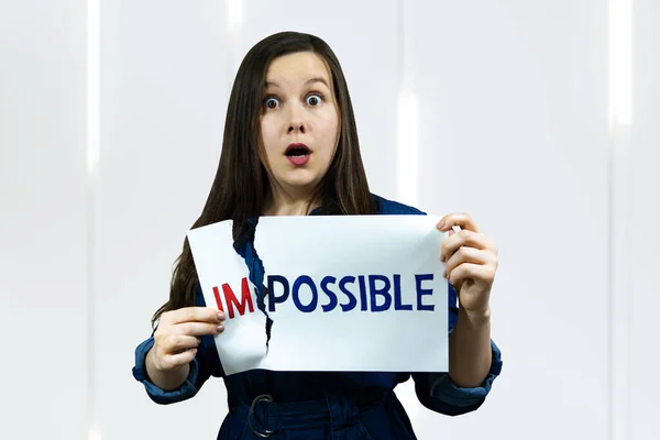 positivity concept, woman tearing word impossible to make possible.