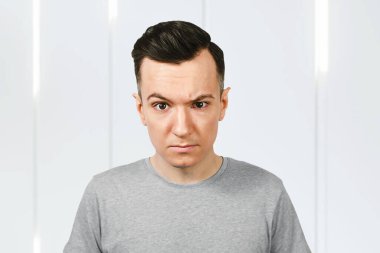 Genç bir adam kaşlarını çatar. Adam üzgün ve mutsuz olduğunu düşünüyor..