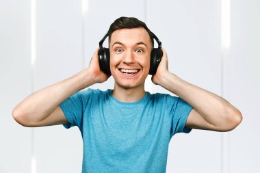 Genç komik adam kulaklıkla müzik dinliyor mavi tişörtlü..