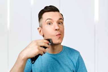 Kesilmemiş genç bir adam makasla kendini kesiyor. Erkek berber saçını tıraş edip, tıraş eder ve saç fırçasıyla kestirir..