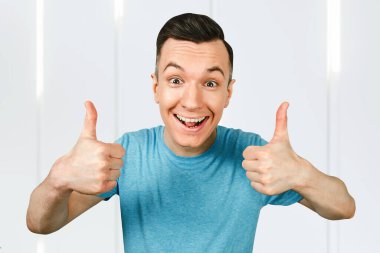 Mavi tişörtlü, gülümseyen genç adam, baş parmağını kaldırdı..