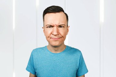 Genç adam kaşlarını çattı. Adam üzgün ve mutsuz olduğunu düşünüyor..