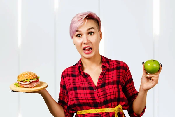 Young Beautiful Girl Smiles Holds Hamburger Green Apple Light Background — 스톡 사진