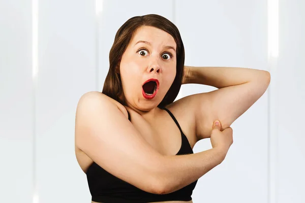 Young fat woman holds on the fat fold on the arm.