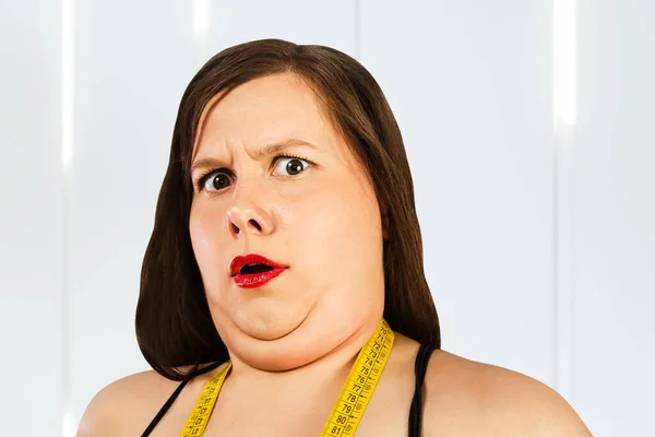 Young fat woman with double chin cry with a meter tape on the neck.