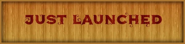 Vintage font text JUST LAUNCHED on square wood panel background.