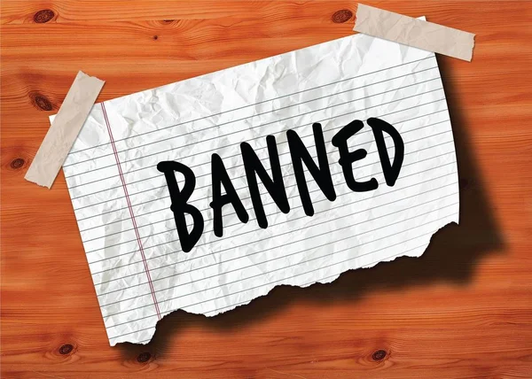 BANNED handwritten on torn notebook page crumpled paper on wood texture background. — Stock Photo, Image