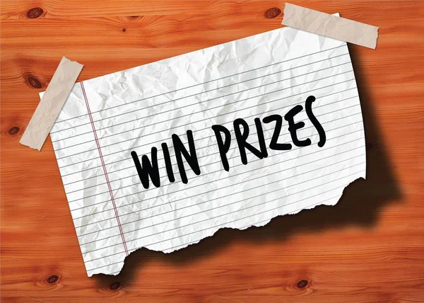 WIN PRIZES handwritten on torn notebook page crumpled paper on wood texture background. — Stock Photo, Image
