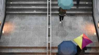Yağmur altında metro istasyonunun girişine doğru yürüyen insanların görüntüsü. Kötü hava.