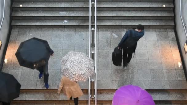 雨の下で地下駅への入り口から歩いていく人々の頭上のビデオクリップ 悪天候 — ストック動画
