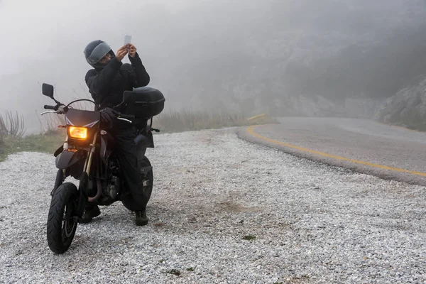 Rider está tentando encontrar sinal em seu celular em um dia nebuloso — Fotografia de Stock