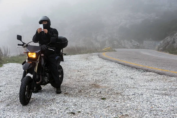 Rider sedang mencoba untuk menemukan sinyal pada ponselnya pada hari berkabut — Stok Foto