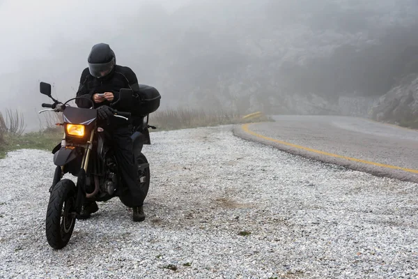 Rider está tentando encontrar sinal em seu celular em um dia nebuloso — Fotografia de Stock