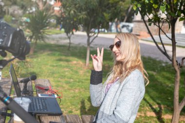 Sarışın kadın blogcu takipçileriyle etkileşime giriyor - açık havada çalışıyor - dünyayı geziyor - youtuber ve etkenler çalışma kavramı