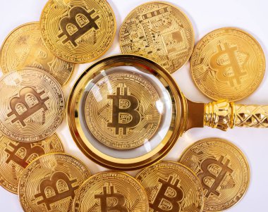 Bozuk paraların bulanık zemininde altın bitcoin büyüteç