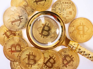 Bozuk paraların bulanık zemininde altın bitcoin büyüteç