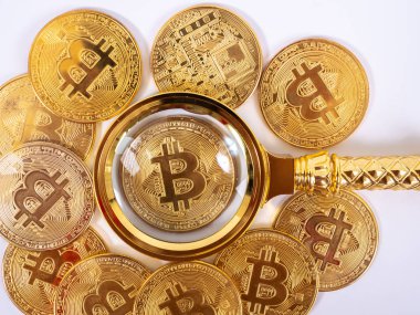 Bozuk paraların bulanık zemininde altın bitcoin büyüteç