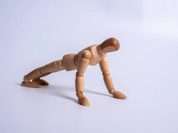 Pequeño maniquí de madera durante flexiones sobre fondo blanco —  Fotos de Stock