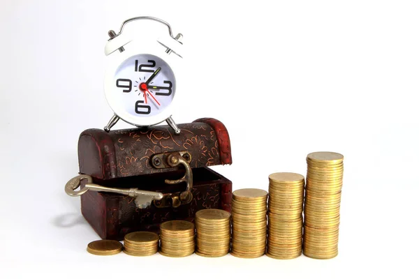 Gold alarm clock lay on money in a wooden chest Stock Image