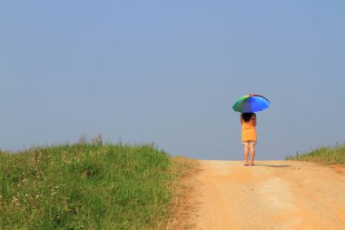Çok renkli şemsiyeler ve mavi gökyüzü tutan güzel bir kadın.