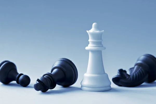 White Chess Queen and black shapes on a light blue background — Stock Photo, Image