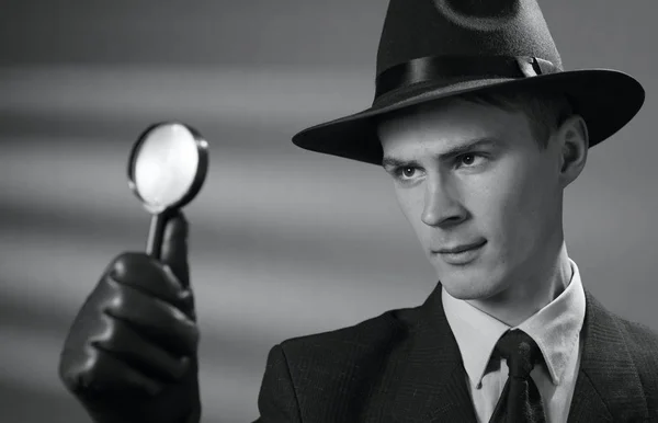 Young vintage detective holding a magnifying glass — Stock Photo, Image