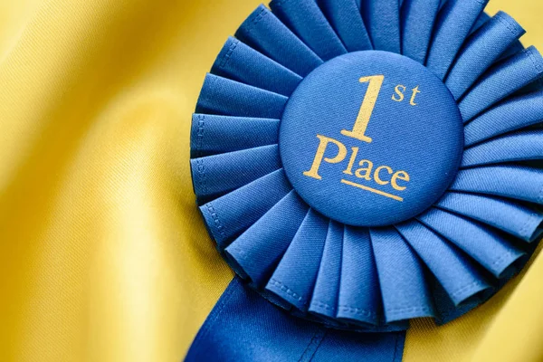 Ist place winners rosette on gold fabric — Stock Photo, Image