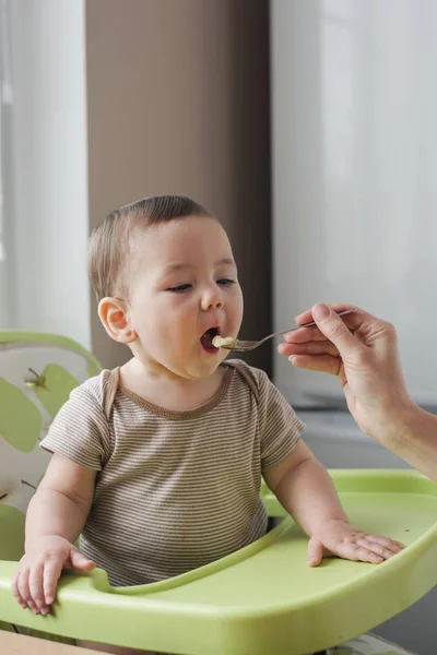 Madre joven alimentando a su hijo pequeño — Foto de Stock