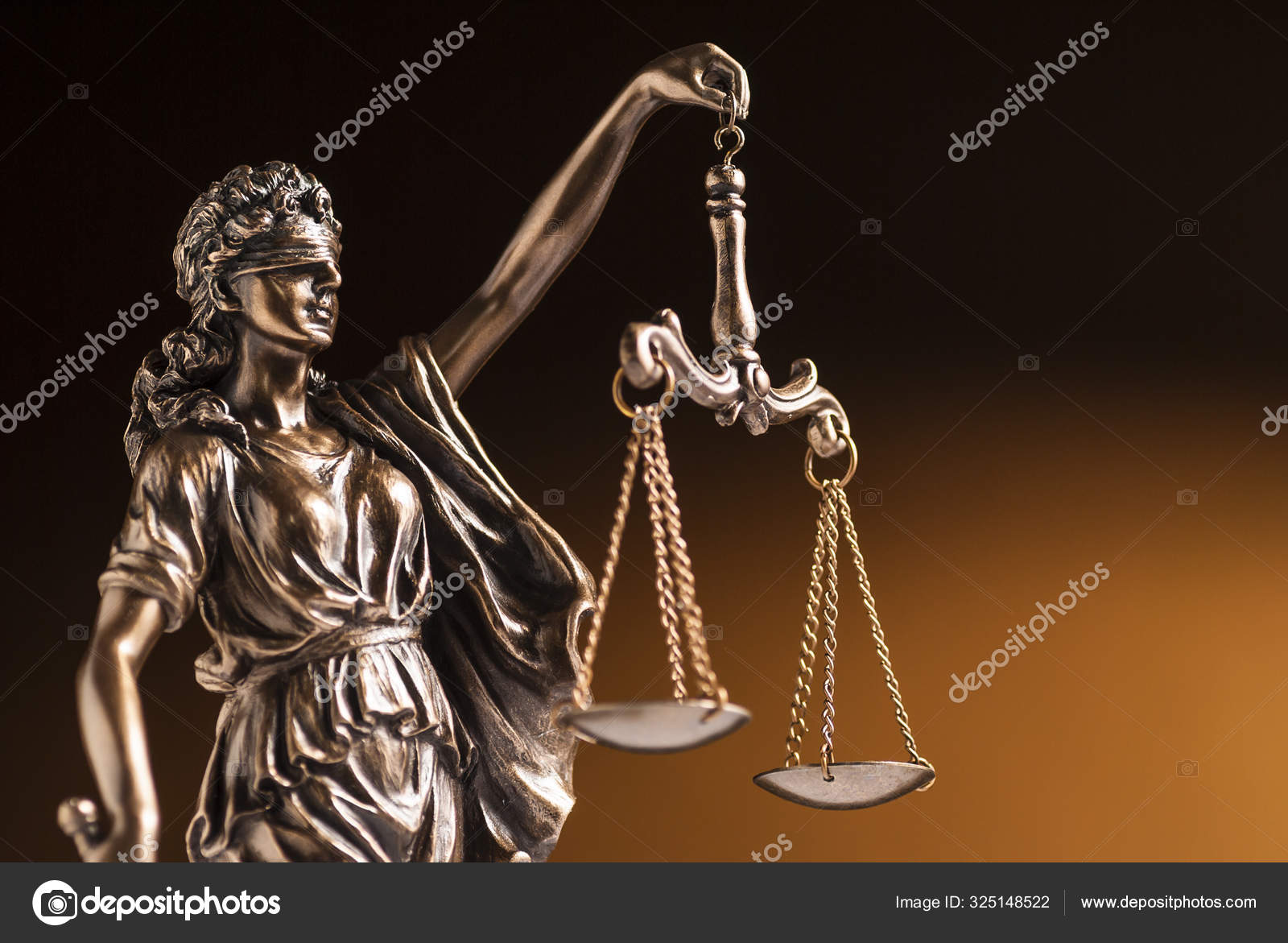 A blindfolded bronze statue of Justice on a brown background Stock