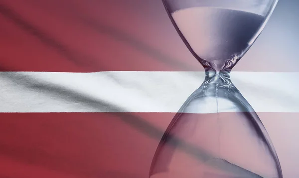 Sanduhr über der Flagge Lettlands — Stockfoto