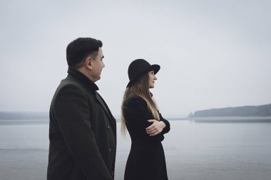 Young couple in a troubled relationship a cold foggy lake in winter