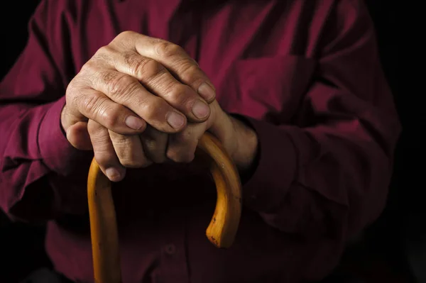 Anciano apoyando sus manos en su bastón — Foto de Stock