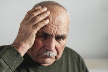 Forgetful senior man holding a hand to his head